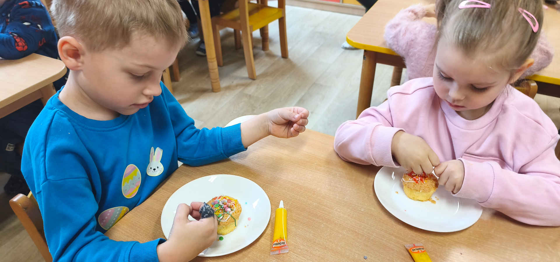 Chłopiec i dziewczynka dekorują babeczki wielkanocne