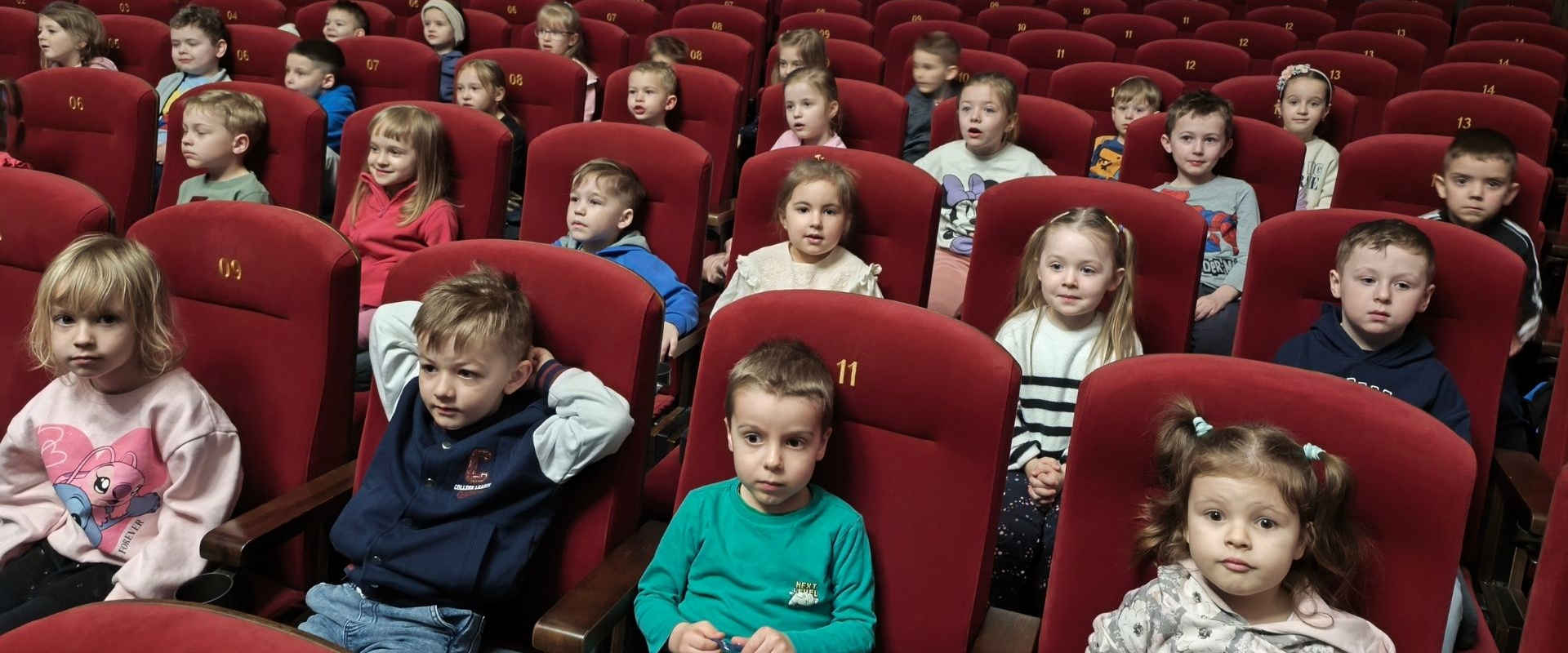 Dzieci siedzą w fotelach w kinie