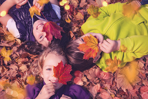 Dzieci leżą w jesiennych liściach